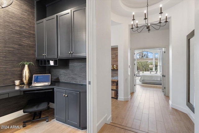 office area with built in desk, a chandelier, and light hardwood / wood-style flooring