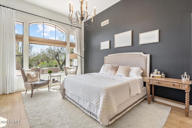 bedroom with multiple windows, light hardwood / wood-style flooring, and a notable chandelier