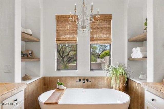 bathroom featuring a bath, built in features, vanity, and a notable chandelier