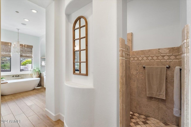 bathroom featuring an inviting chandelier, tile walls, and separate shower and tub