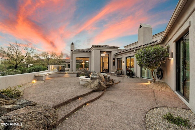 back house at dusk featuring a patio area