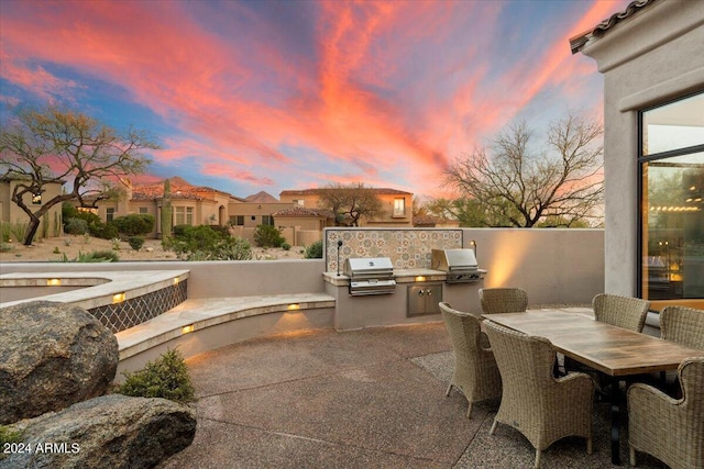 patio terrace at dusk with area for grilling and exterior kitchen