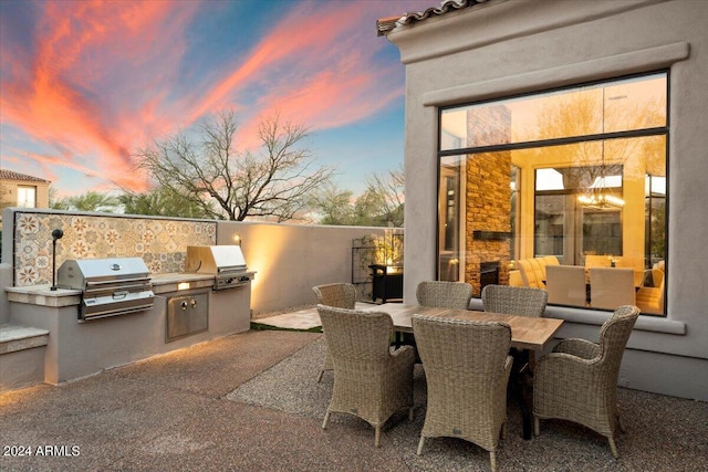 patio terrace at dusk featuring grilling area and area for grilling