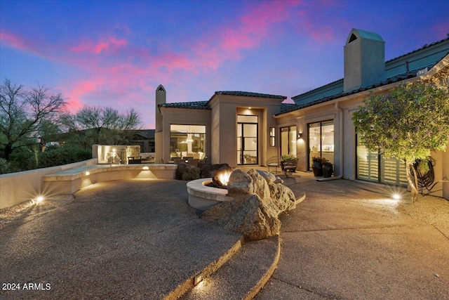 back house at dusk with an outdoor fire pit and a patio area