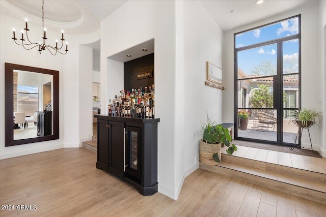 interior space featuring light hardwood / wood-style floors, a tray ceiling, pendant lighting, a chandelier, and crown molding