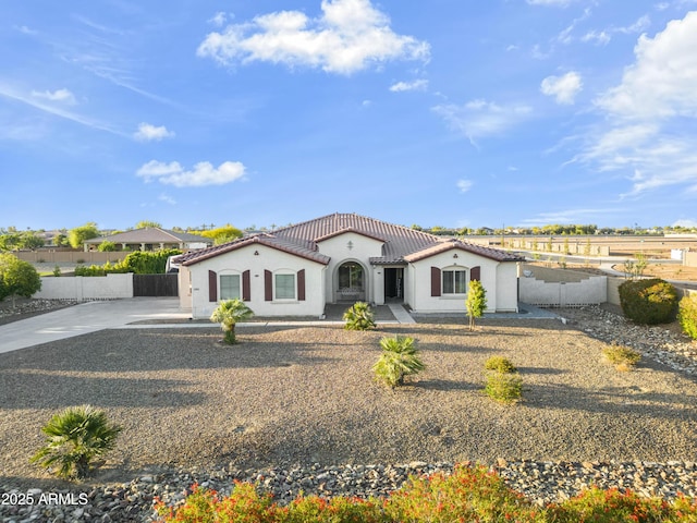 ranch-style home featuring a tile roof, driveway, stucco siding, and fence