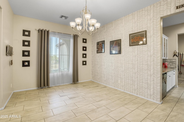 interior space with a notable chandelier, visible vents, baseboards, an accent wall, and wallpapered walls