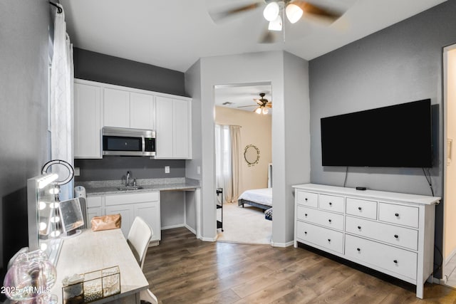 kitchen featuring stainless steel microwave, white cabinetry, a sink, dark wood-style flooring, and a ceiling fan