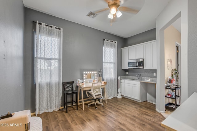 kitchen featuring stainless steel microwave, white cabinets, a sink, ceiling fan, and visible vents