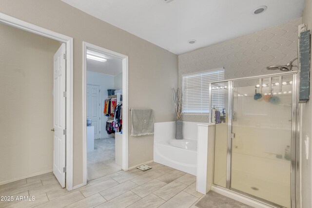 bathroom featuring a garden tub, a walk in closet, and a shower stall