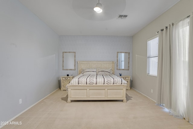 bedroom featuring visible vents, light colored carpet, and baseboards