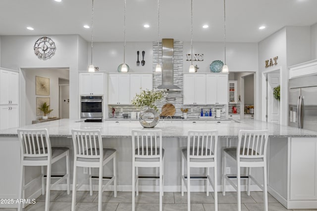 kitchen with a large island, white cabinets, wall chimney range hood, and tasteful backsplash