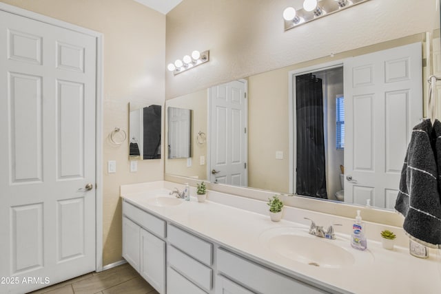 bathroom with toilet, double vanity, and a sink