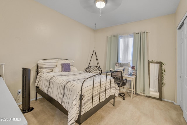 bedroom featuring light colored carpet, ceiling fan, baseboards, and a closet