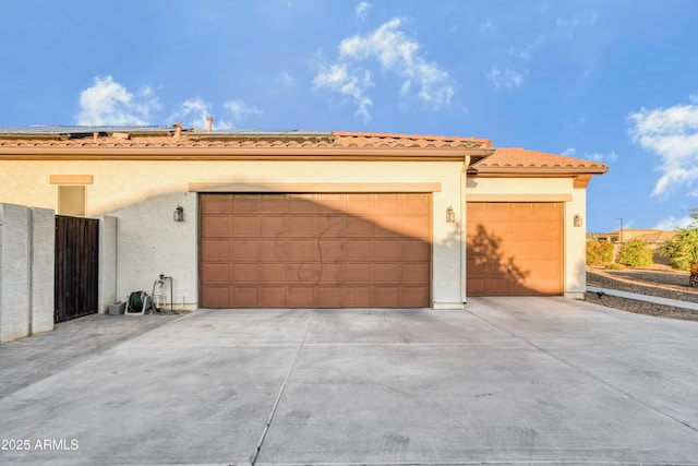 exterior space featuring an attached garage, concrete driveway, stucco siding, and a tiled roof