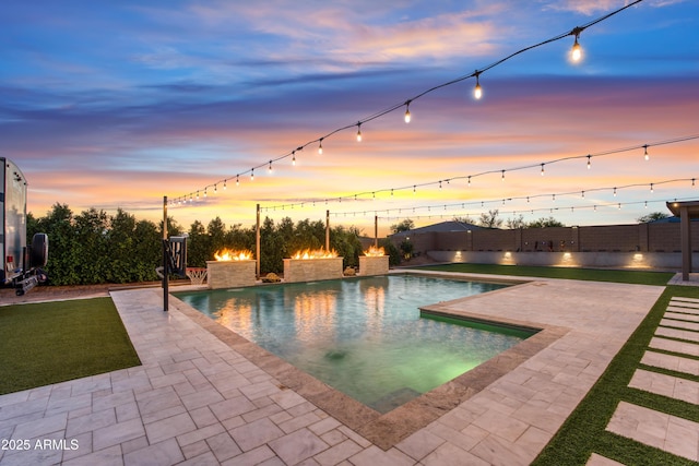 pool at dusk featuring a fenced backyard, a patio, and a fenced in pool