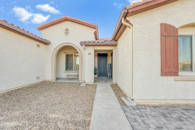 view of exterior entry featuring stucco siding and a tile roof