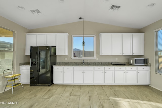 kitchen with a sink, black fridge, white microwave, visible vents, and lofted ceiling