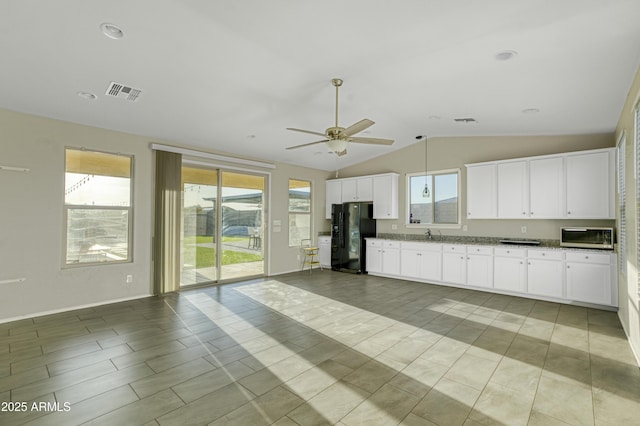 kitchen with lofted ceiling, visible vents, black refrigerator with ice dispenser, and a healthy amount of sunlight