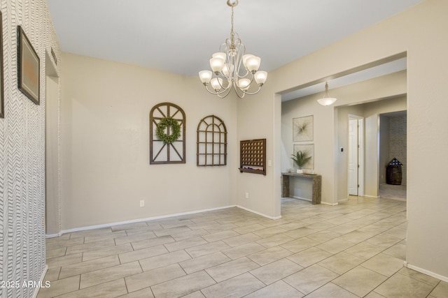 spare room featuring a notable chandelier and baseboards