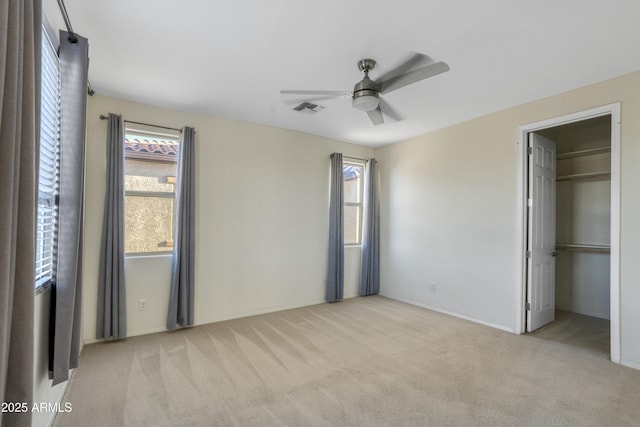 unfurnished bedroom with carpet, visible vents, and multiple windows