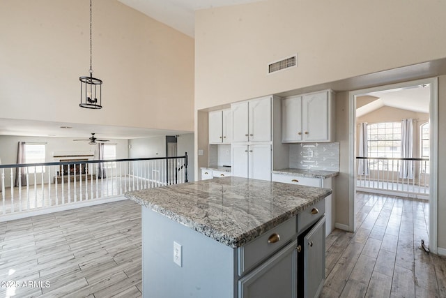 kitchen featuring backsplash, white cabinets, light wood-style flooring, and ceiling fan
