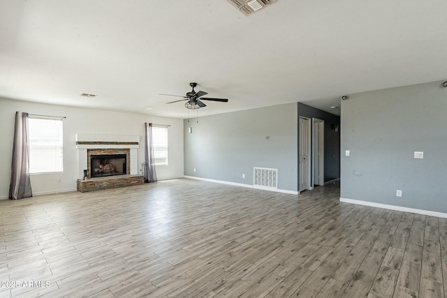 unfurnished living room featuring a wealth of natural light, visible vents, and wood finished floors