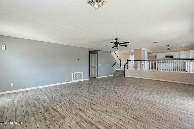 unfurnished living room with baseboards, ceiling fan, visible vents, and light wood finished floors
