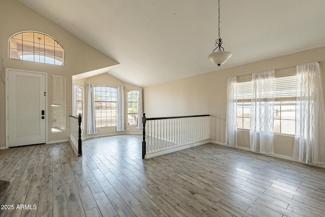 entrance foyer featuring baseboards, vaulted ceiling, and wood finished floors