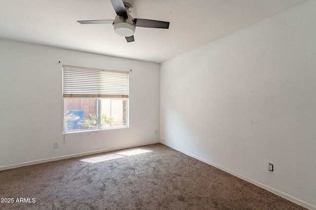 carpeted spare room with a ceiling fan and baseboards