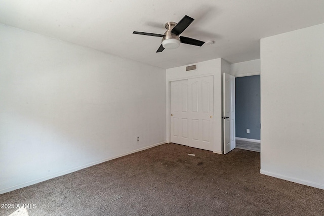 empty room with visible vents, baseboards, dark carpet, and ceiling fan