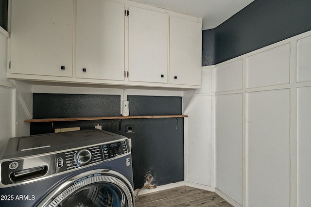 clothes washing area featuring cabinet space, wood finished floors, and washer / dryer