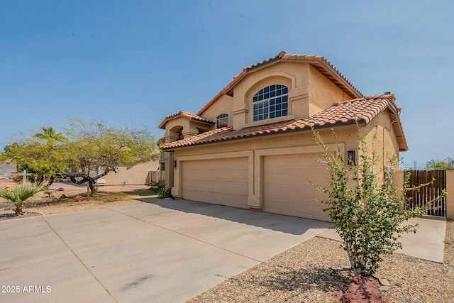 mediterranean / spanish house with a tile roof, driveway, a garage, and stucco siding
