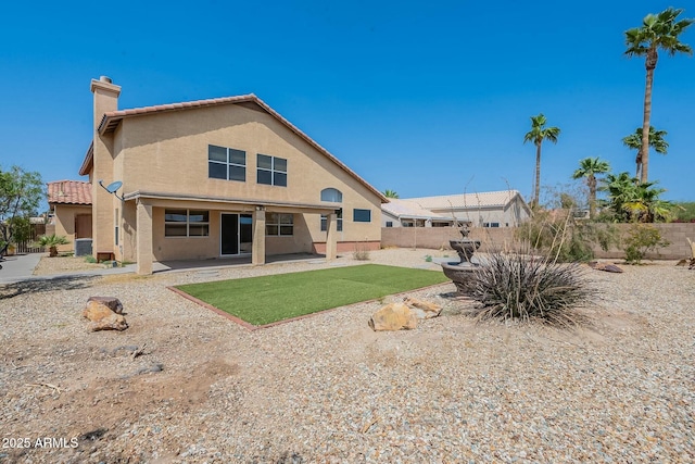 back of property with fence, a patio, a chimney, a tile roof, and stucco siding