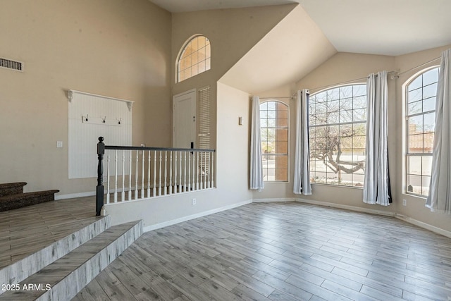 foyer entrance featuring wood finished floors, baseboards, a healthy amount of sunlight, and visible vents