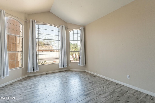 spare room featuring baseboards, lofted ceiling, and wood finished floors