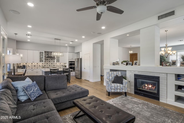living room featuring ceiling fan with notable chandelier and light hardwood / wood-style floors