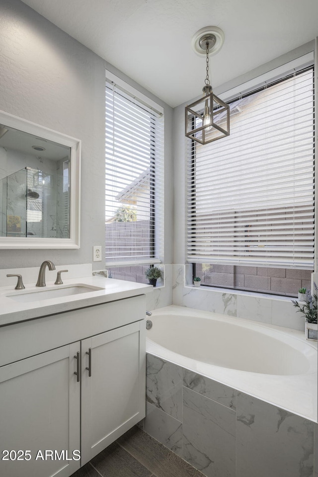 bathroom with vanity, a notable chandelier, hardwood / wood-style flooring, and plus walk in shower