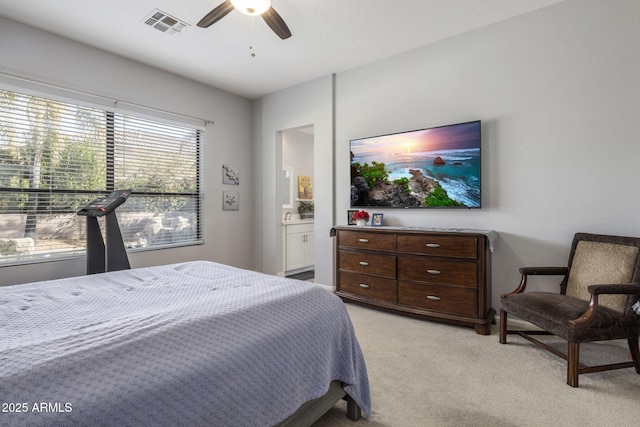 bedroom with ceiling fan, ensuite bath, and light colored carpet