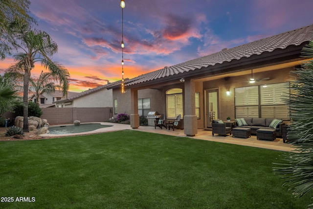 back house at dusk with a lawn, outdoor lounge area, and a patio area
