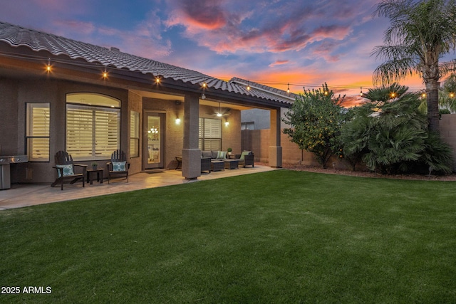 back house at dusk featuring an outdoor living space, a yard, and a patio