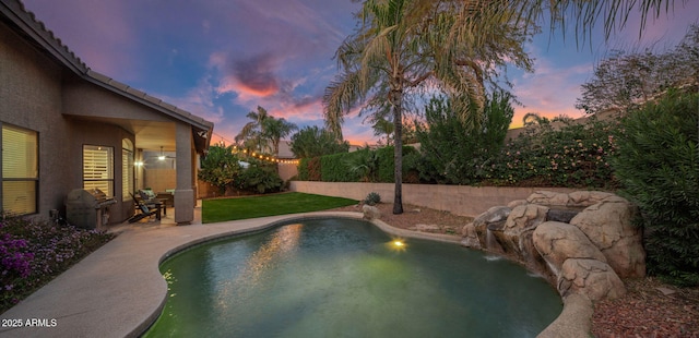 pool at dusk featuring pool water feature and a patio area