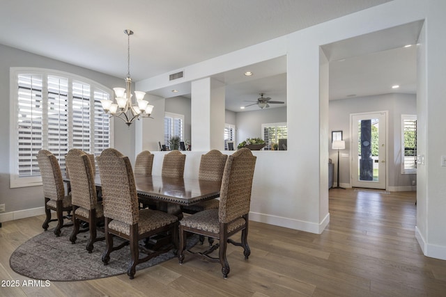 dining area with hardwood / wood-style floors and ceiling fan with notable chandelier