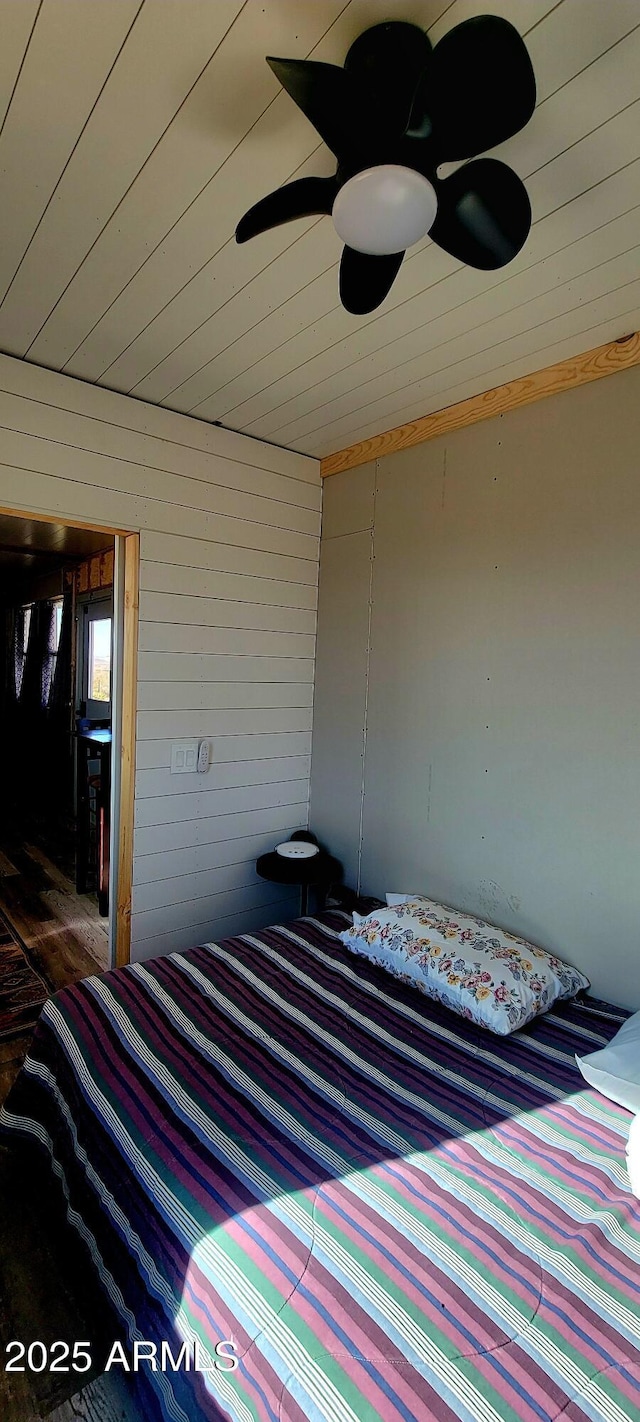 bedroom featuring ceiling fan, wood walls, and wood ceiling
