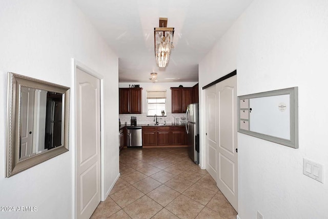 kitchen with appliances with stainless steel finishes, sink, light tile patterned floors, and tasteful backsplash