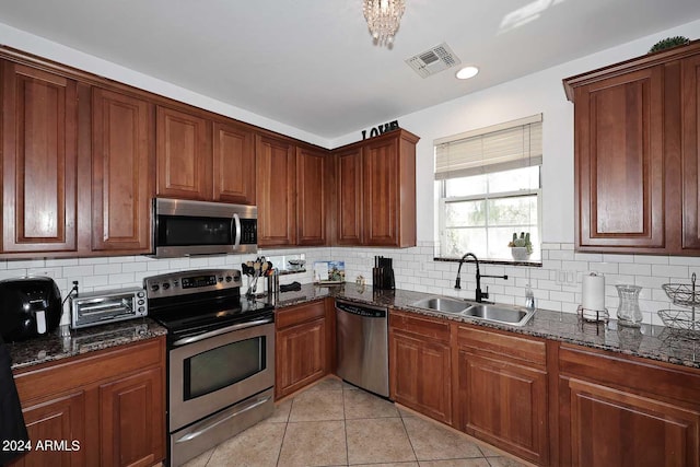 kitchen featuring light tile patterned flooring, sink, tasteful backsplash, appliances with stainless steel finishes, and dark stone countertops