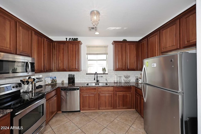 kitchen featuring dark stone counters, appliances with stainless steel finishes, tasteful backsplash, and sink