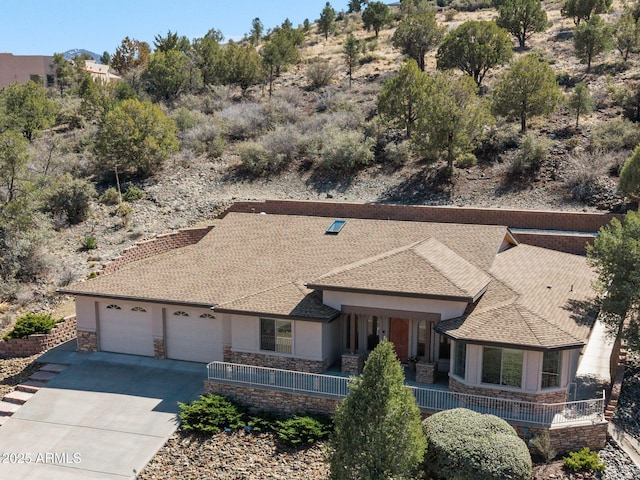 view of front facade featuring stone siding, concrete driveway, a garage, and a shingled roof