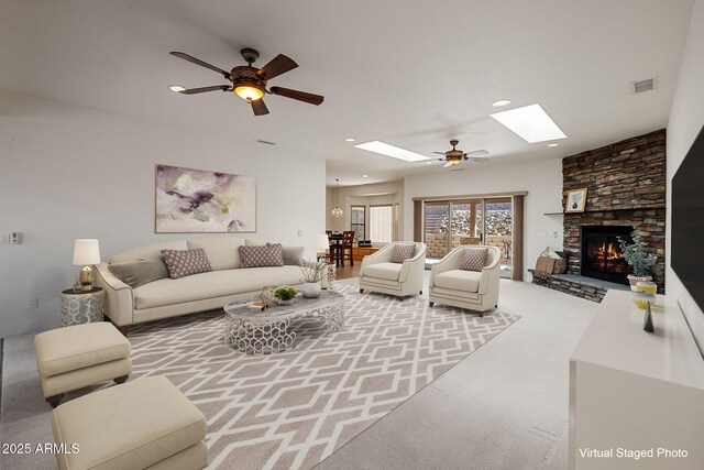 living area featuring visible vents, carpet, a skylight, a fireplace, and ceiling fan