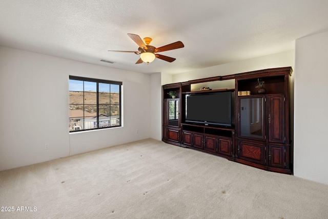 unfurnished living room with visible vents, a textured ceiling, carpet, and a ceiling fan